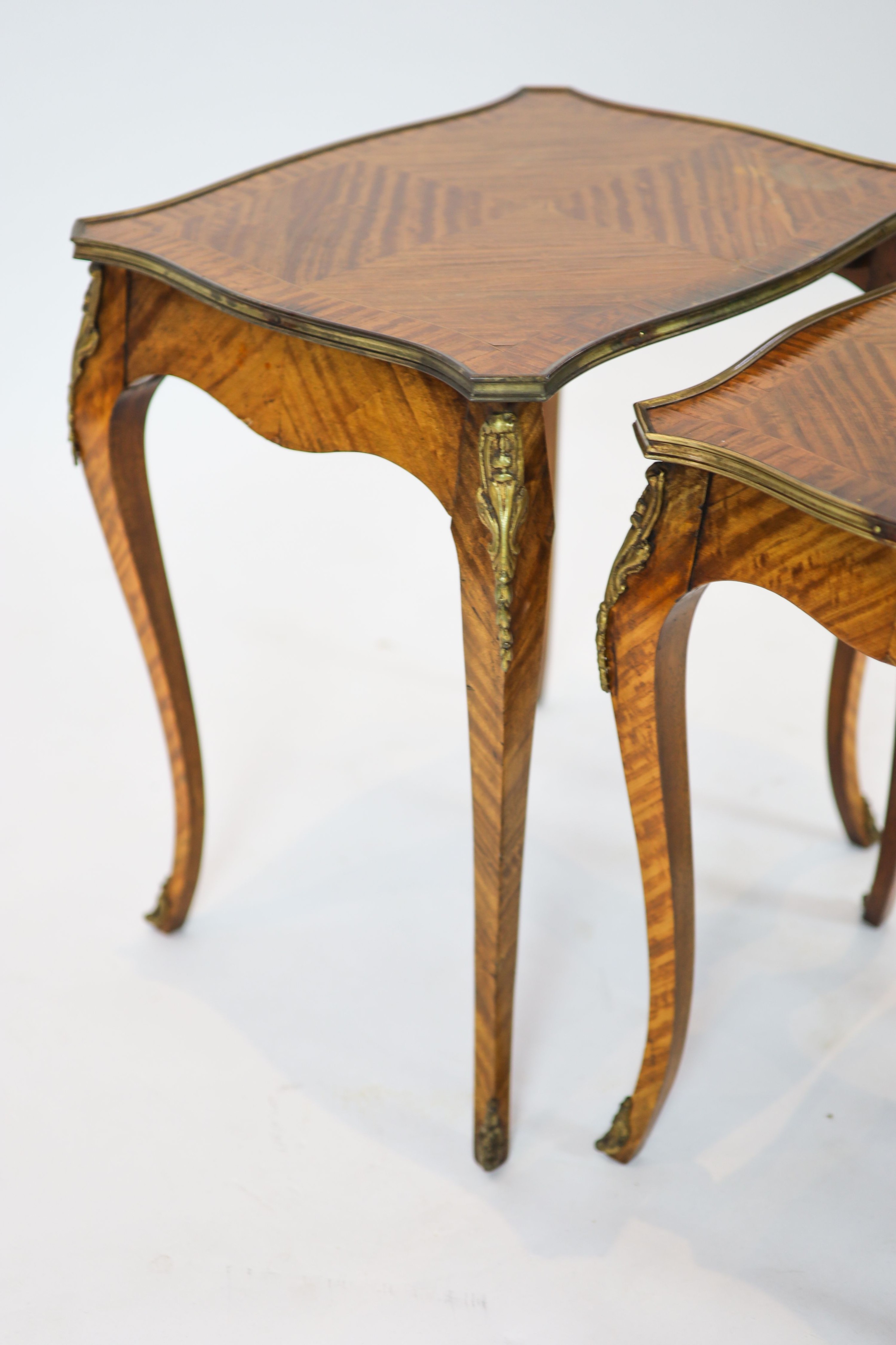 A nest of three Louis XV style ormolu mounted banded kingwood tables, with serpentine sides, on cabriole legs, width 51cm, depth 41cm, height 59cm